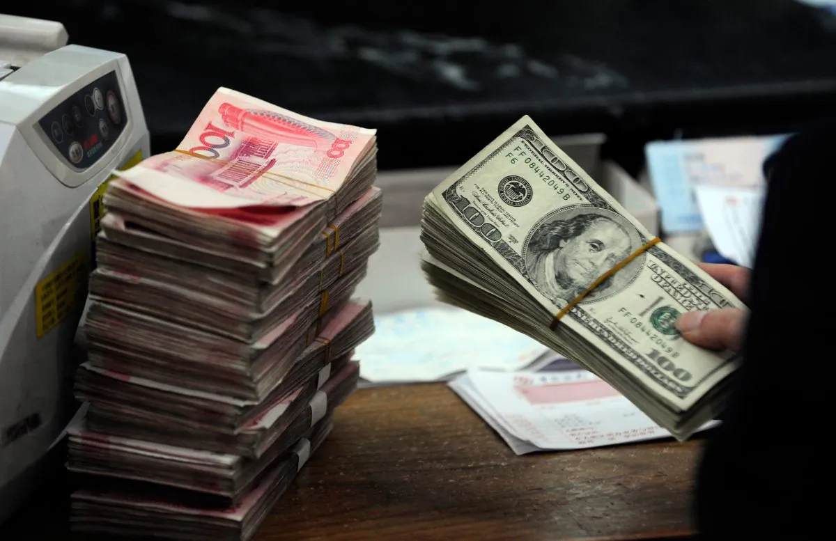 A Chinese bank teller prepares to count a stack of U.S. dollars together with stacks of 100 Chinese yuan notes at a bank in Hefei, Anhui Province, China on March 9, 2010. (STR/AFP/Getty Images)
