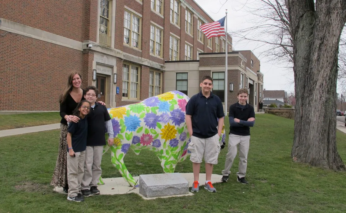 Teacher Kelly Gasior (L) and students stand with a statue of a Buffalo that's been emblazoned with anti-bullying messages outside Lorraine Academy, Public School No. 72, in Buffalo, N.Y. Educators in Buffalo and elsewhere worry the name-calling, mocking and social media attacks that have gotten applause in the presidential campaign could undermine schools' bullying prevention policies that call for kindness and respect. (AP Photo/Carolyn Thompson)
