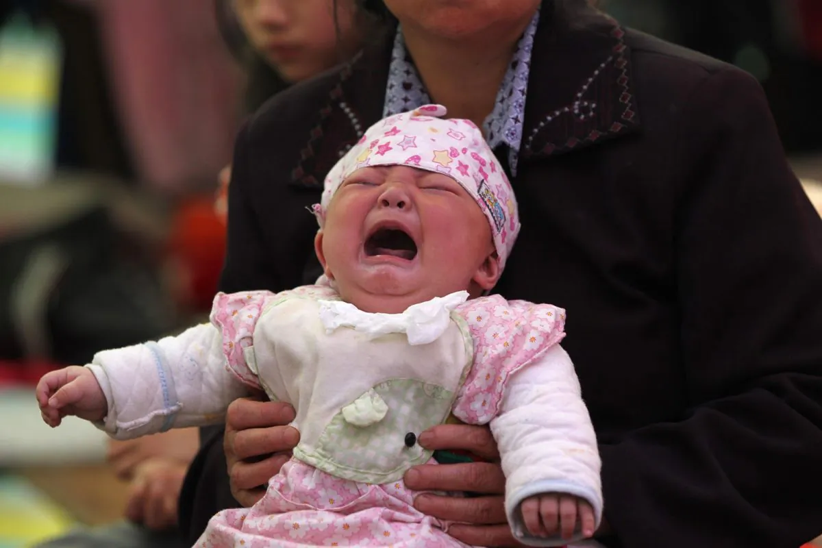 This photo taken on April 23, 2013 shows 4-month-old Li Jie crying in her mother's arms inside a temporary settlement in Lingguan township of Baoxing county in Yaan, southwest China's Sichuan province. (AFP/AFP/Getty Images)