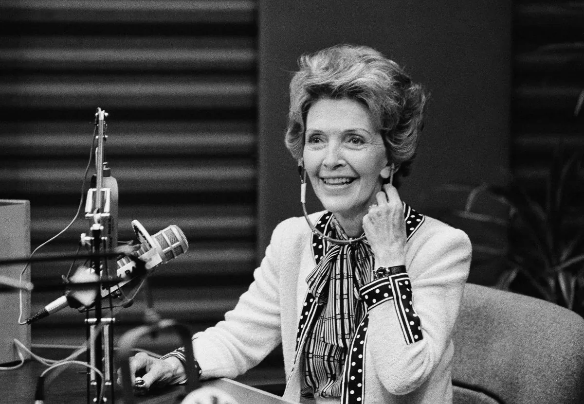 First lady Nancy Reagan smiles as she adjusts her headphones during a guest spot on a radio talk show, Oct.7, 1982 in Los Angeles.  Mrs. Reagan spent most of the 45-minute stint on KABC's show discussing and answering telephone callers' questions about the Foster Grandparents program. (AP Photo/Wally Fong)