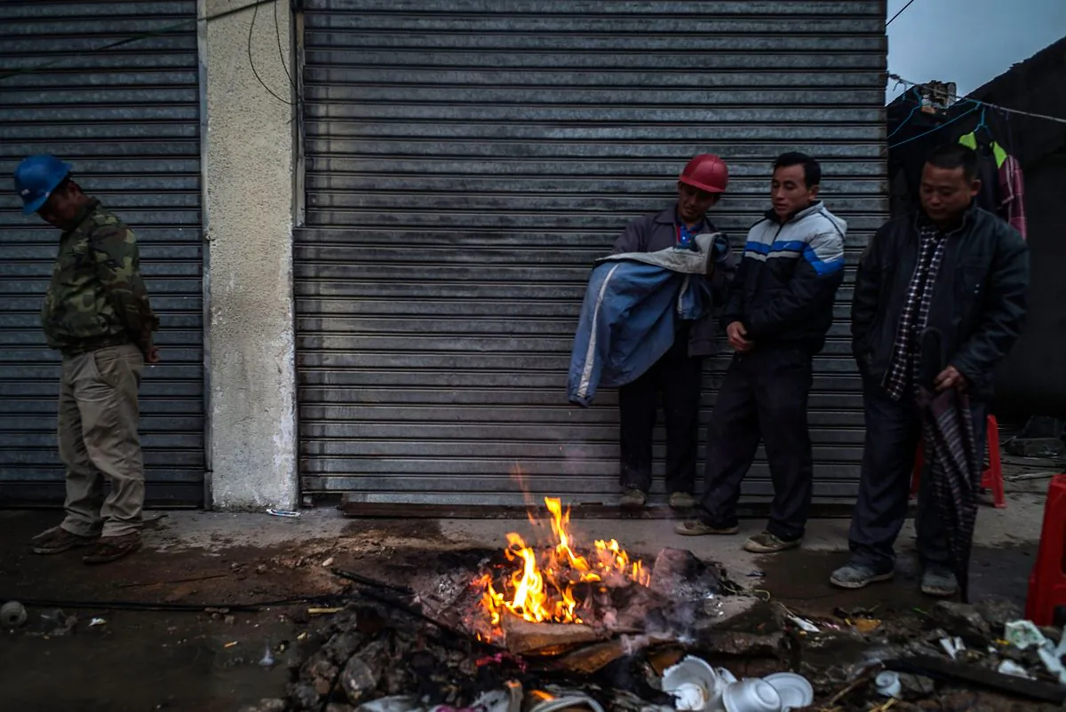 Workers keep warm next to a bonfire at a demolished industrial area at Houjie town in Dongguan, China, on Jan. 26. (Lam Yik Fei/Getty Images)
