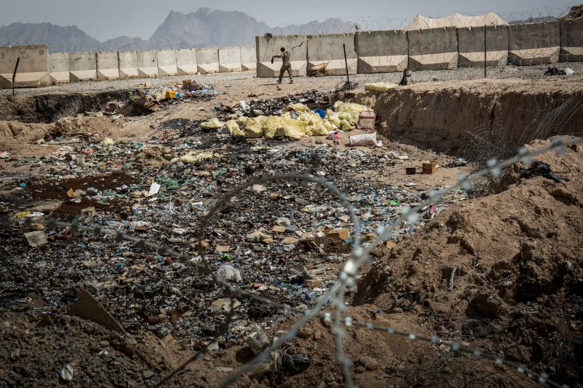 A soldier in the Afghan National Army walks past a burn pit at a command outpost  in Kandahar Province, Zhari District, Afghanistan, on March 22, 2013. (Andrew Burton/Getty Images)