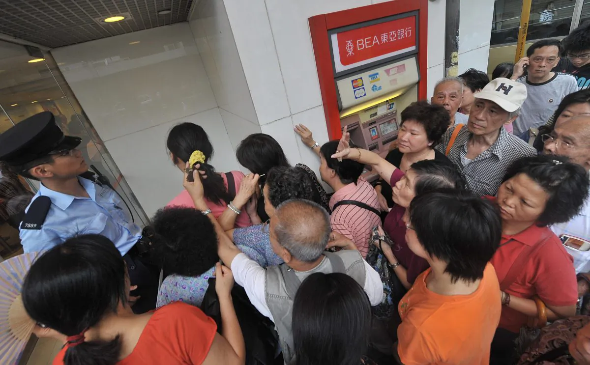 A policeman (L-in blue shirt) tries to assist customers as they crowd the entrance of a branch of Hong Kong's Bank of East Asia (BEA) on September 24, 2008. (MIKE CLARKE/AFP/Getty Images)