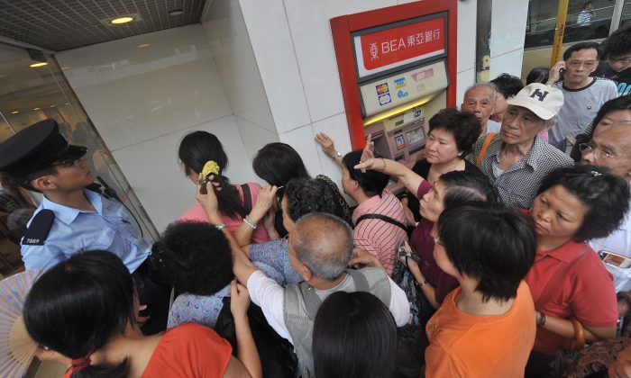 A policeman (L-in blue shirt) tries to assist customers as they crowd the entrance of a branch of Hong Kong's Bank of East Asia (BEA) on September 24, 2008. (MIKE CLARKE/AFP/Getty Images)