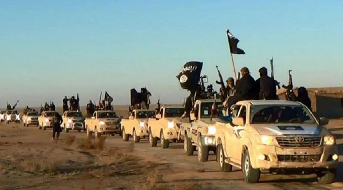 In this undated file photo released online in the summer of 2014 on a militant social media account, which has been verified and is consistent with other AP reporting, ISISI militants hold up their weapons and wave its flags on their vehicles in a convoy on a road leading to Iraq, in Raqqa, Syria. (Militant photo via AP)