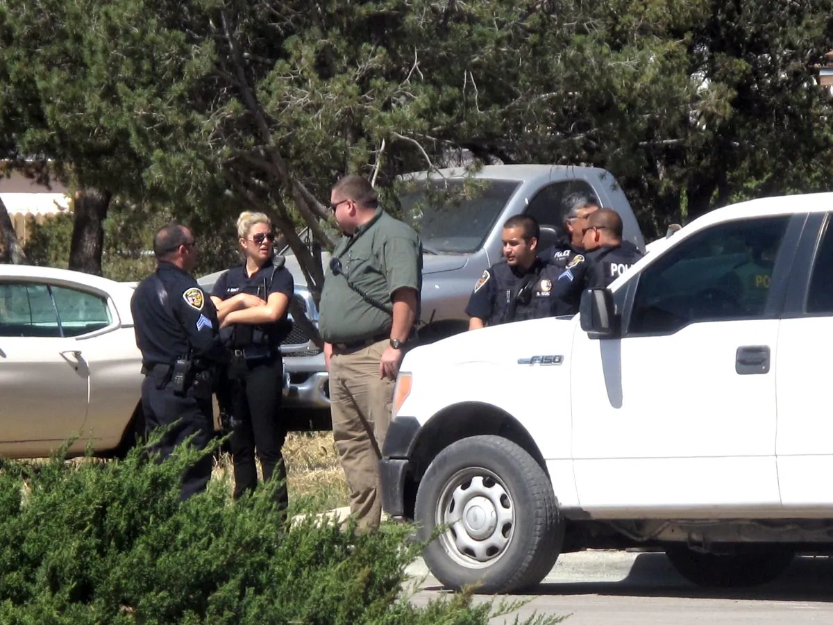 Artesia Police Department officers join New Mexico State Police, SWAT, and other agencies gather while investigating a lead in the morning at a home in Artesia, N.M., on March 10, 2016. Authorities were searching Thursday for two violent convicts who escaped from a prisoner transport van and likely got a head start of several hours in a remote area of New Mexico before guards realized they were gone. (Brienne Green/Artesia Daily Press via AP)