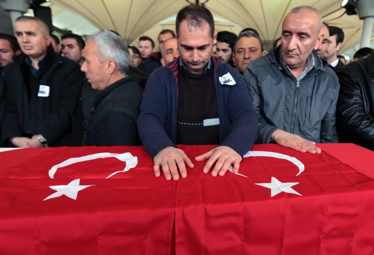 People stand by the Turkish flag-draped coffin of Murat Gul, 20, a security agent killed at Sunday's explosion during his funeral procession in Ankara, Turkey, Monday, March 14, 2016. A senior government official told The Associated Press that authorities believe the attack was carried out by two bombers, one of them a woman, and was the work of Kurdish militants. It was the second deadly attack blamed on Kurdish militants in the capital in the past month. (AP Photo/Burhan Ozbilici)