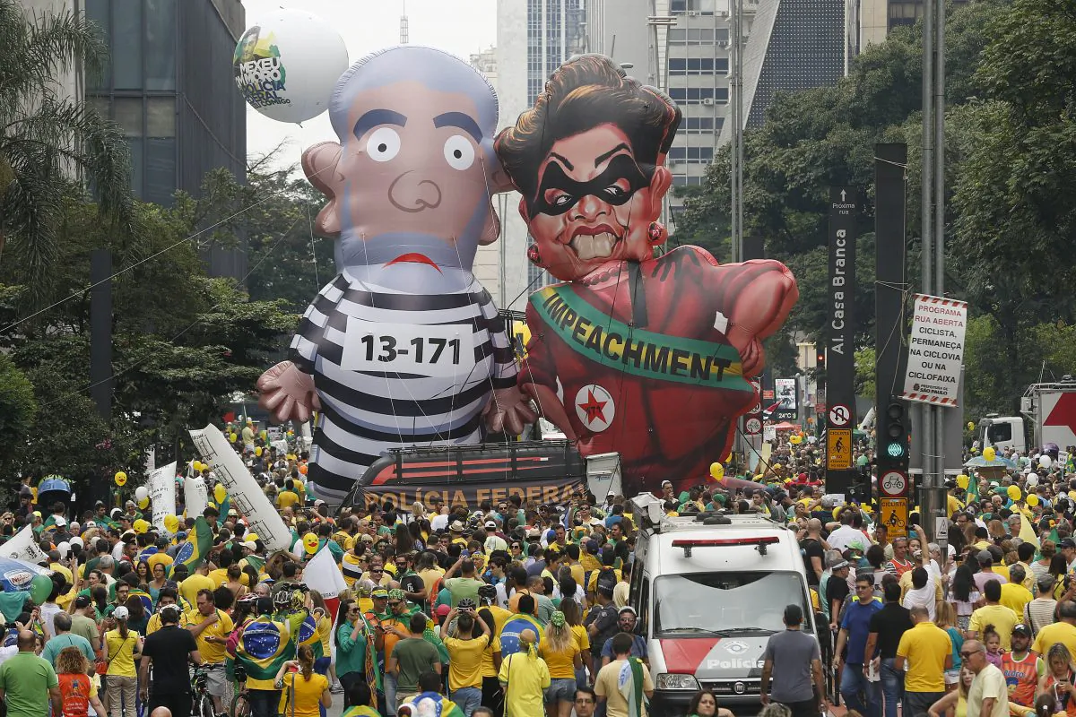 Demonstrators parade large inflatable dolls depicting Brazil's former President Luiz Inacio "Lula" da Silva in prison garb and current President Dilma Rousseff dressed as a thief, with a presidential sash that reads "Impeachment," in Sao Paulo, Brazil, on March 13, 2016. The corruption scandal at the state-run oil giant Petrobras has ensnared key figures from Rousseff’s Workers’ Party, including her predecessor and mentor, Lula da Silva, as well as members of opposition parties. (AP Photo/Andre Penner)