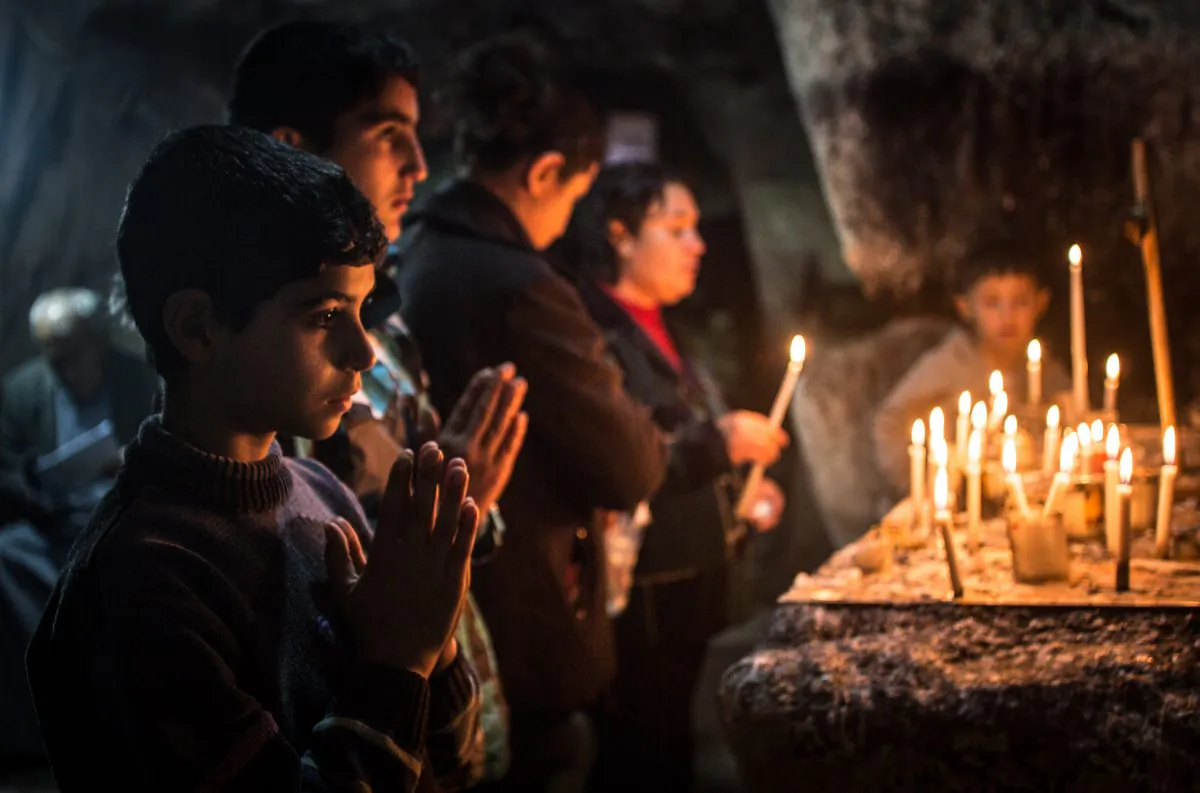 Iraqi Christians light candles inside a shrine on the grounds of Mazar Mar Eillia (Mar Elia) Catholic Church, that has now become home to hundreds of them, forced to flee their homes due to the Islamic State advances, in Erbil, Iraq, on Dec. 12, 2014. (Matt Cardy/Getty Images)