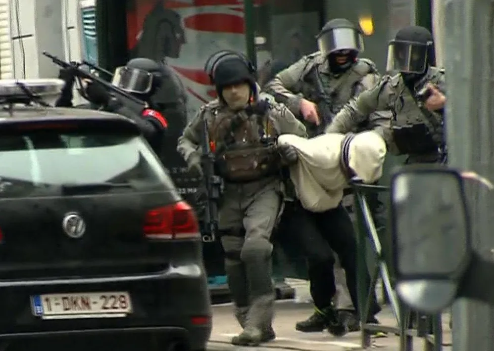 Armed police officers escort Salah Abdeslam to a police vehicle during a raid in the Molenbeek neighborhood of Brussels, Belgium, on March 18, 2016. (VTM via AP) BELGIUM OUT
