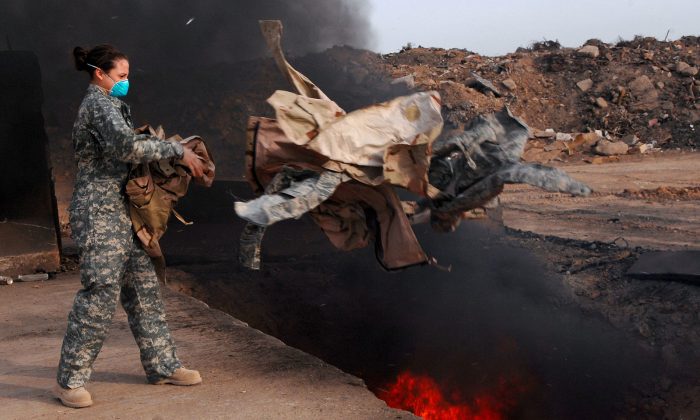 U.S. Air Force Senior Airman Frances Gavalis, 332nd Expeditionary Logistics Readiness Squadron equipment manager, tosses unserviceable uniform items into a burn pit at Balad Air Base, Iraq, on March 10, 2008. Military uniform items turned in must be burned to ensure they cannot be used by opposing forces. (U.S. Department of Defense, Public Domain)