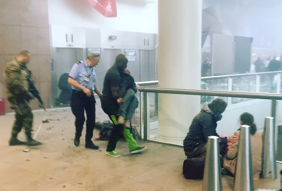 Alphonse Youla carries a victim of the Brussels airport attacks to safety on March 22, 2016. (Ketevan Kardava/ Georgian Public Broadcaster via AP)