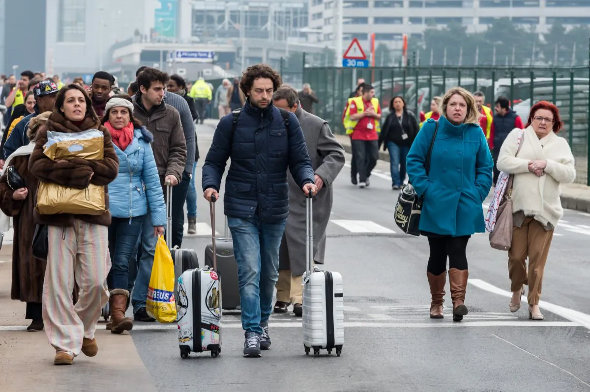 People walk away from Brussels airport after explosions rocked the facility in Brussels, Belgium Tuesday March 22, 2016.   (AP Photo/Geert Vanden Wijngaert)