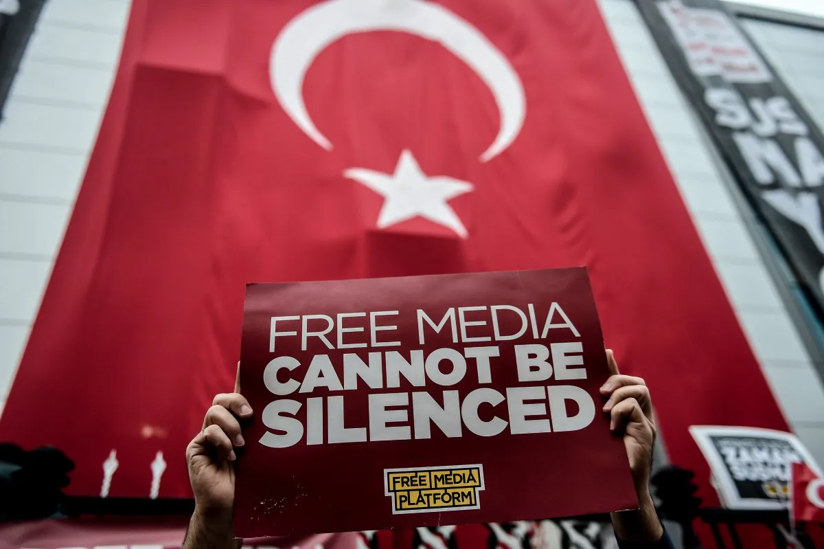 A supporter of the Bugun Newspaper and Kanalturk holds a placard during a rally outside its headquarters covered with the Turkish national flag during a protest in Istanbul on Oct. 27, 2015, against the Turkish government's crackdown on media outlets. (Ozan Kose/AFP/Getty Images)