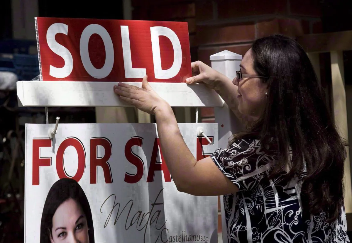 A report by RBC Economics says housing affordability continued to decline in Toronto and Vancouver, while conditions for homebuyers improved in Alberta during the first quarter of the year as lower oil prices caused the real estate market to soften. A real estate agent puts up a "sold" sign in front of a house in Toronto Tuesday, April 20, 2010. THE CANADIAN PRESS/Darren Calabrese