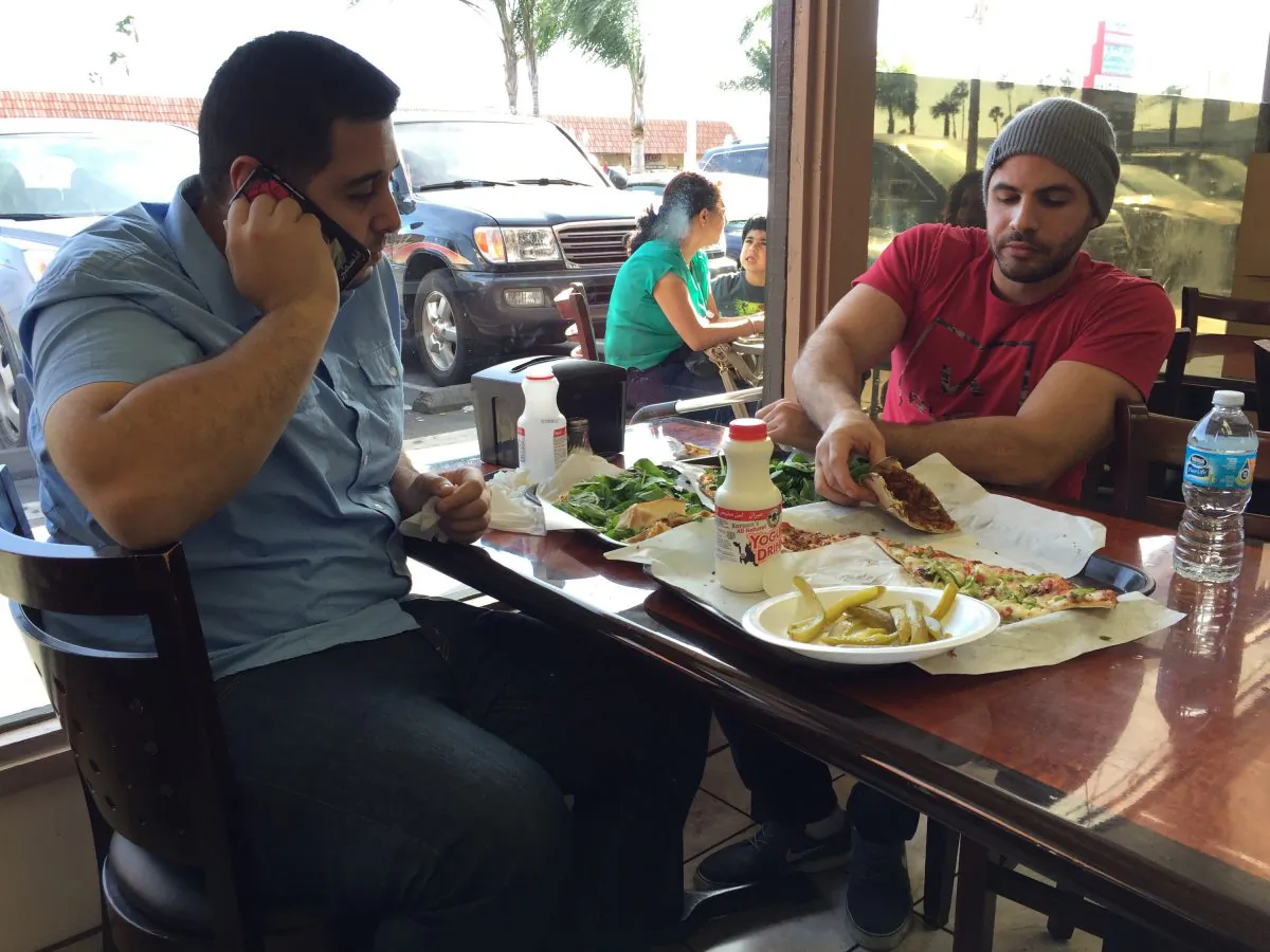 Nas Juma, 22, left, and Omar Ghanim, 23, enjoy Lebanese pizza at Forn Al Hara restaurant in Orange County's Little Arabia in Anaheim, Calif., on March 22, 2016. (Gillian Flaccus/AP Photo)