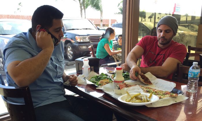 Nas Juma, 22, left, and Omar Ghanim, 23, enjoy Lebanese pizza at Forn Al Hara restaurant in Orange County's Little Arabia in Anaheim, Calif., on March 22, 2016. (Gillian Flaccus/AP Photo)