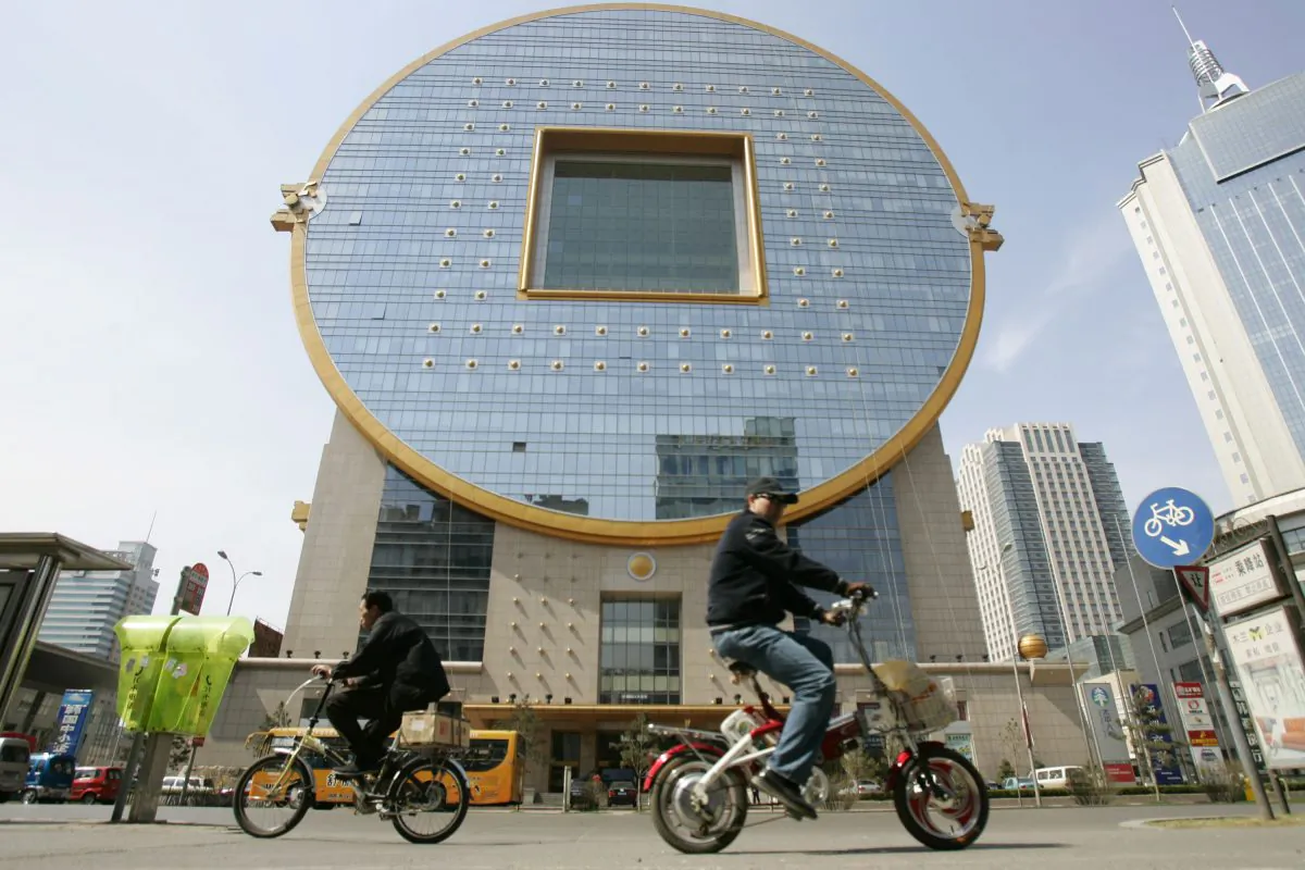 People pedal past a building shaped as a Chinese ancient coin on April 21, 2007 in Shenyang of Liaoning Province, China. (China Photos/Getty Images)