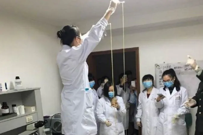 A doctor holds up the tapeworm before medicals staff. (via China Times News)