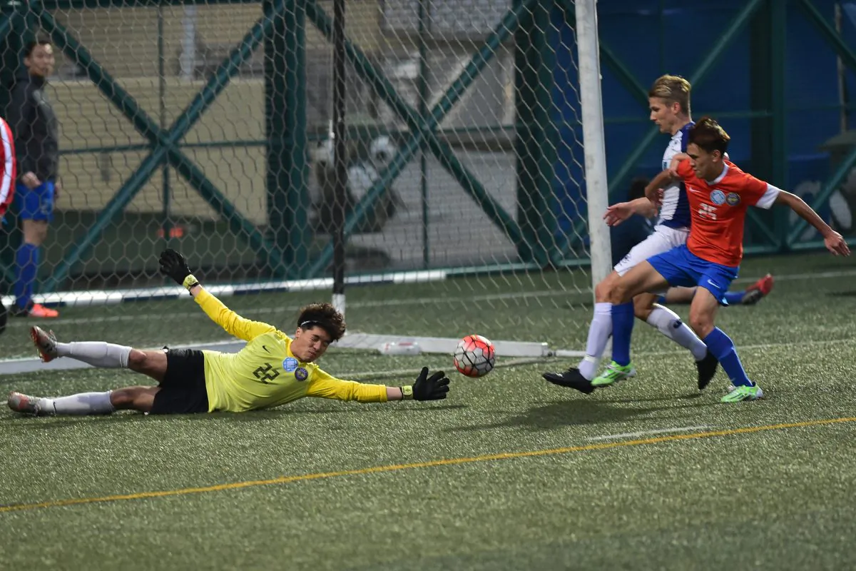 Frederick Schipper of HKFC (blue and white kit) scores in the HKFA First Division match against Kwun Tong at Sports Road on Sunday March 20,2016. HKFC won the match 6-0. (Bill Cox/Epoch Times)