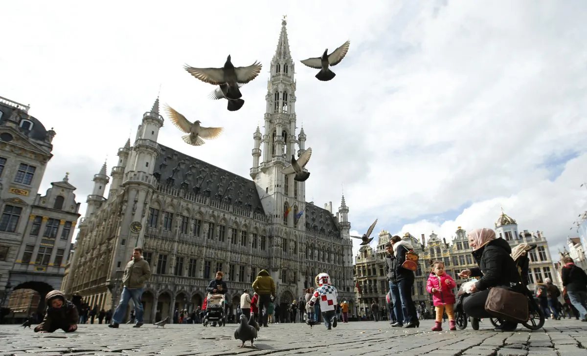 Pigeons take flight as tourists feed them in the Grand Place in Brussels on March, 28, 2016. The Belgian health minister says four of those wounded in the suicide bombings last week have died in the hospital. (AP Photo/Alastair Grant)