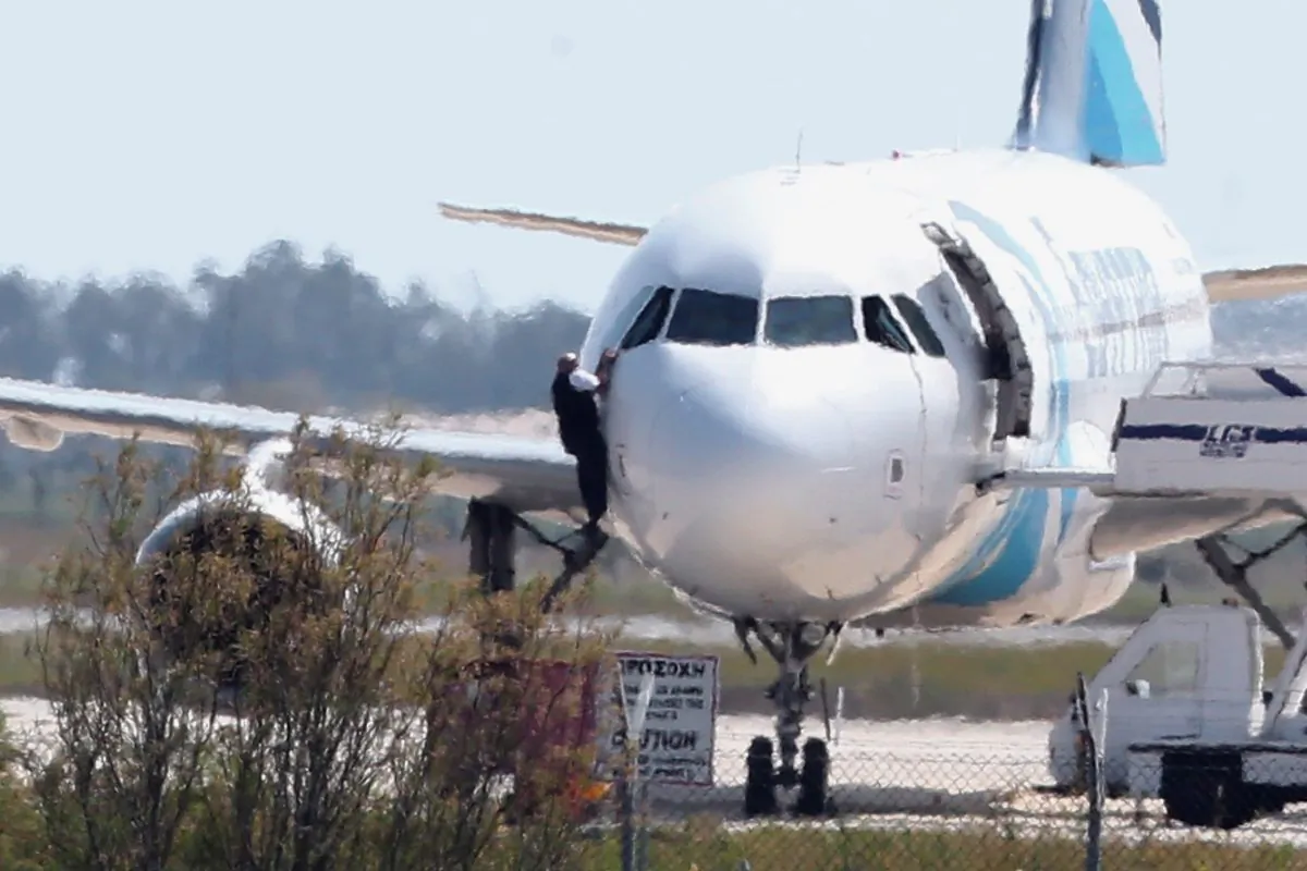 A man leaves the hijacked aircraft of Egyptair from pilot window at Larnaca airport in Cyprus Tuesday, March 29, 2016. (AP Photo/Petros Karadjias)