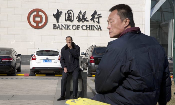Chinese men sit outside the Bank of China headquarters in Beijing, China, on Feb. 25, 2016. (AP Photo/Ng Han Guan)
