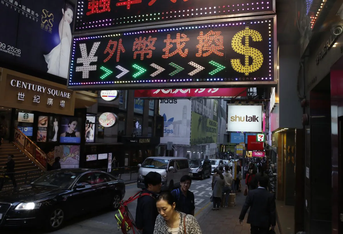 People walk under a sign for foreign currency exchange in Hong Kong on March 2, 2016. China and Hong Kong are emerging as a global hub for money laundering. (Kin Cheung/AP Photo)
