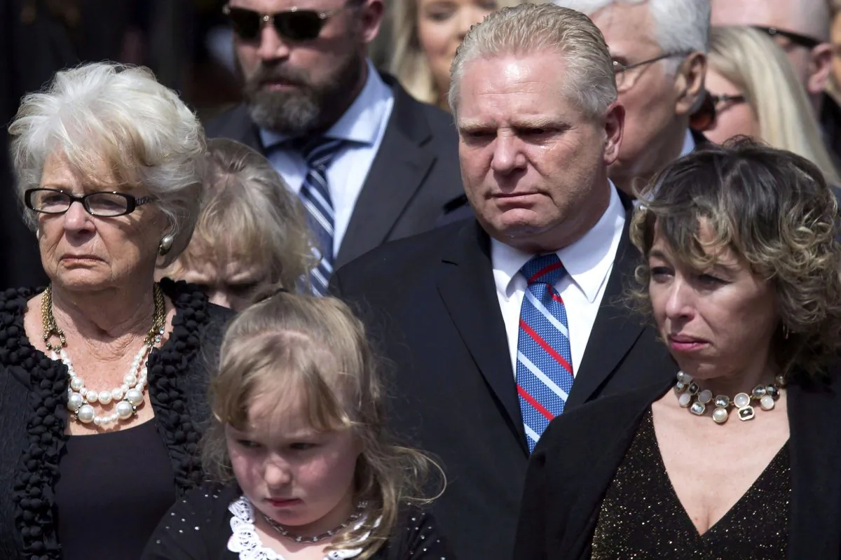A tear rolls down Doug Ford’s cheek as he stands with his mother Diane (L), sister-in-law Renata (R), and niece Stephanie as they watch former Toronto mayor Rob Ford's casket being placed into a hearse following a funeral service at St. James Cathedral on March 30, 2016. (The Canadian Press/Chris Young)