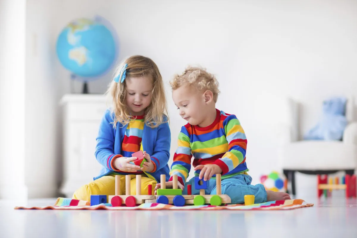 Children playing with wooden train. (FamVeld/iStock)