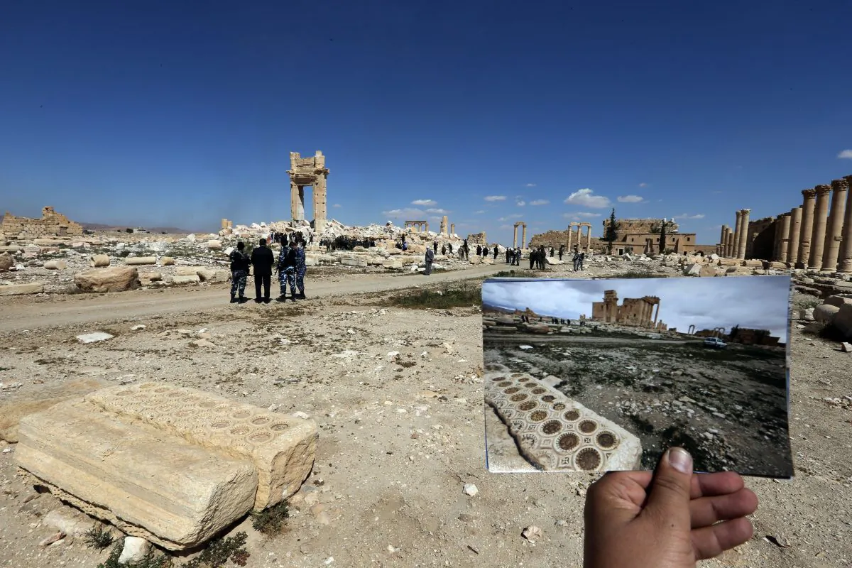 A general view taken on March 31, 2016 shows a photographer holding his picture of the Temple of Bel taken on March 14, 2014 in front of the remains (far-L) of the historic temple after it was destroyed by Islamic State (IS) group jihadists in September 2015 in the ancient Syrian city of Palmyra.
Syrian troops backed by Russian forces recaptured Palmyra on March 27, 2016, after a fierce offensive to rescue the city from jihadists who view the UNESCO-listed site's magnificent ruins as idolatrous.

 / AFP / JOSEPH EID        (Photo credit should read JOSEPH EID/AFP/Getty Images)
