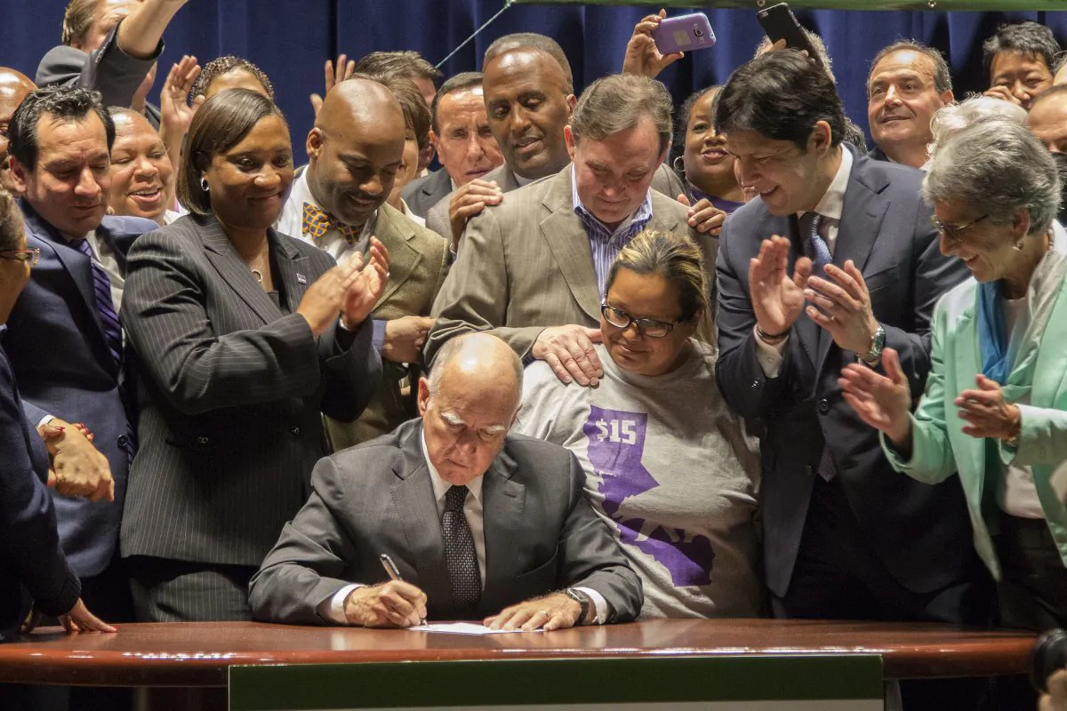 California Governor Jerry Brown signs landmark legislation SB 3 into law in Los Angeles on April 4, 2016. (David McNew/Getty Images)