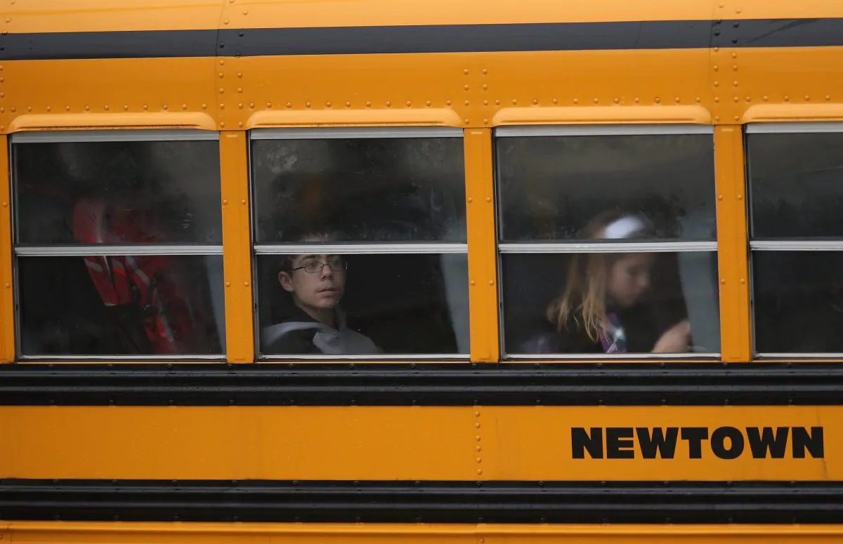 Children return to school on December 18, 2012 in Newtown, Connecticut. Four days after 20 children and six adults were killed at Sandy Hook Elementary School. (Photo by John Moore/Getty Images)