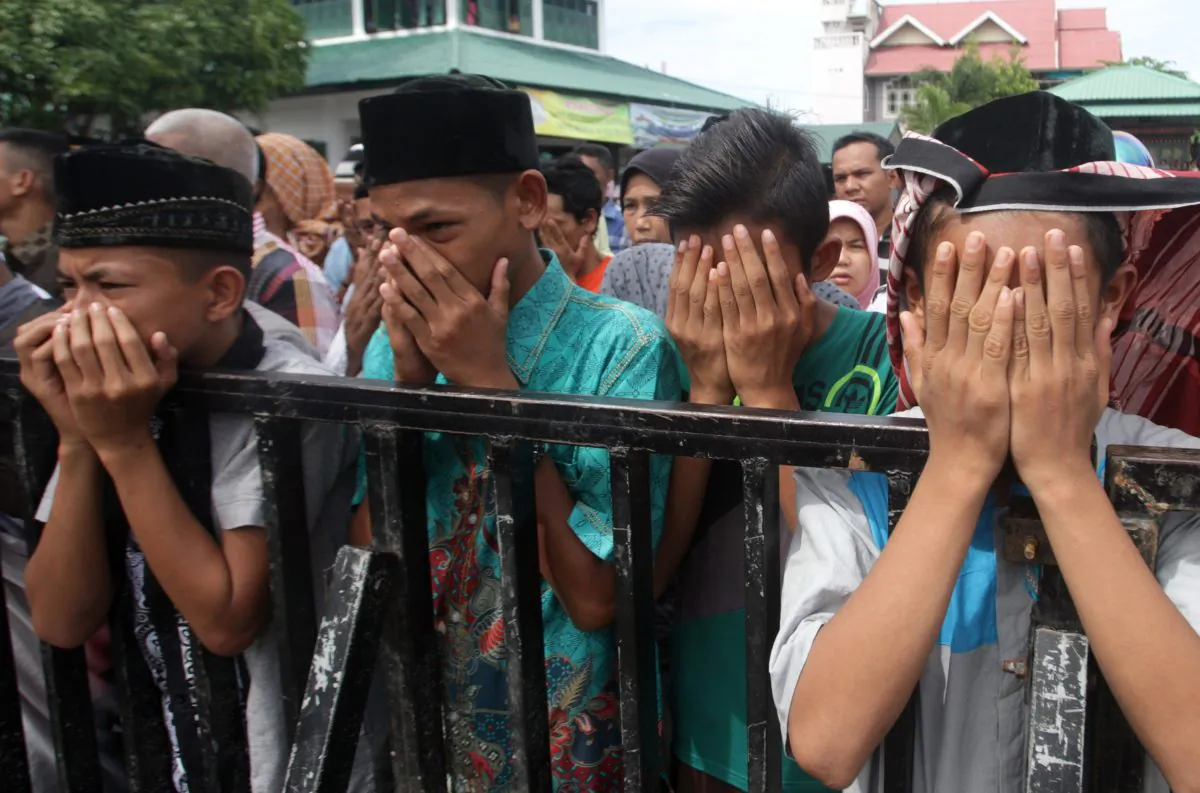 Acehnese youths react as they watch a public caning for those who are convicted of violating local Sharia law, in Banda Aceh, Aceh province, Indonesia, Friday, Nov. 6, 2015. (AP Photo/Heri Juanda)