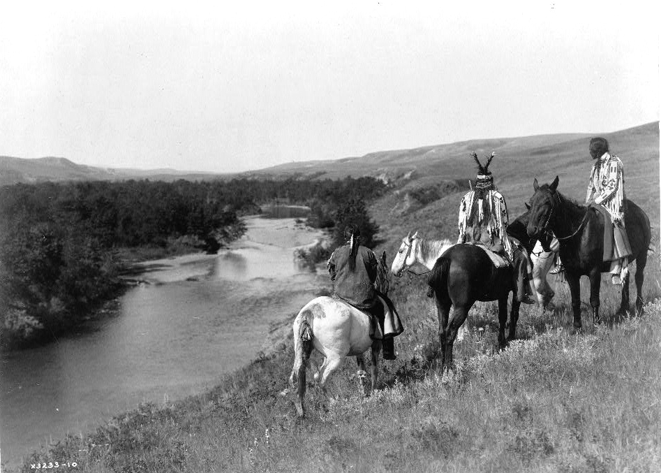 Three Piegan Indians and four horses on hill above river, 1910. (Edward S. Curtis/Library of Congress)