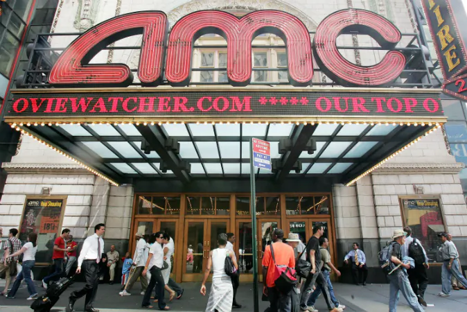 Pedestrians pass an AMC movie theater in Times Square June 21, 2005 in New York City. AMC Entertainment Inc. announced plans to acquire Loews Cineplex Entertainment Corp. to form a combined company called AMC Entertainment Inc. which will have interests in about 450 movie theaters. (Photo by Mario Tama/Getty Images)