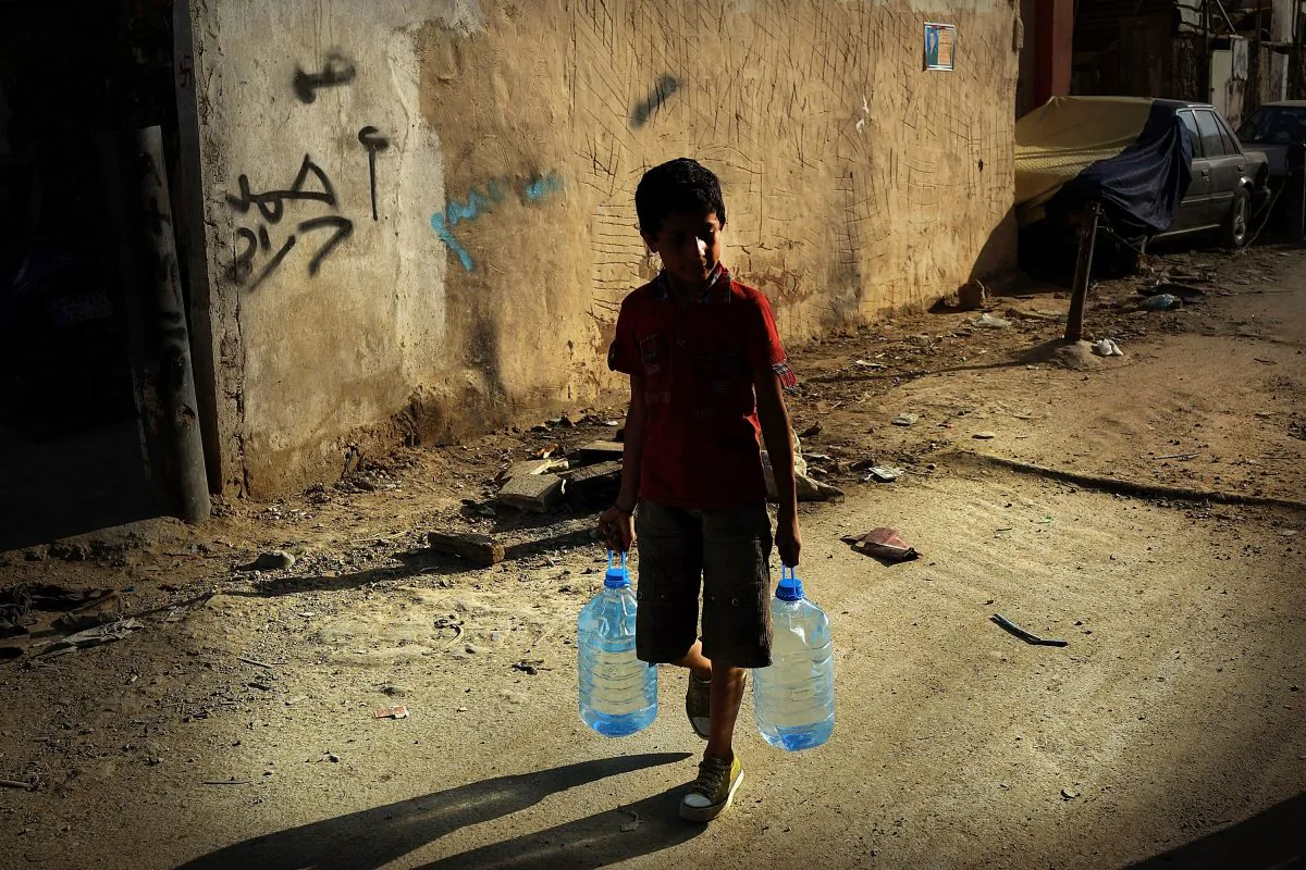 A boy walks with jugs of water in a poor neighborhood with a high concentration of Syrian refugees in Beirut, Lebanon, on June 27, 2013. (Spencer Platt/Getty Images)