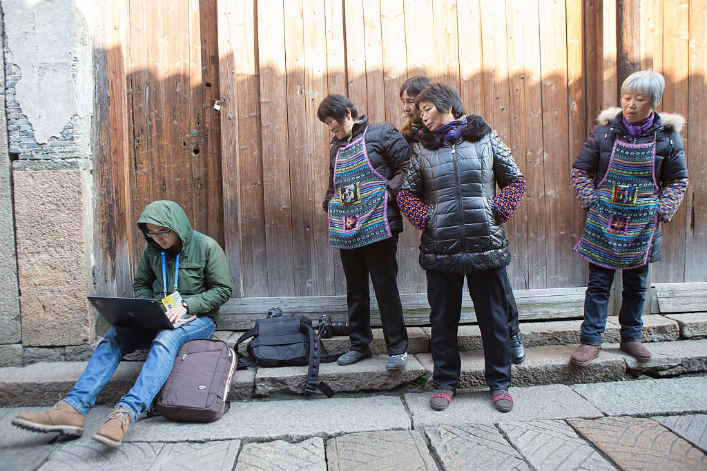 Several citizens crowd to look at a Shanghai reporter acting on press releases about the Second World Internet Conference in Wuzhen ancient town on December 16, 2015 in Jiaxing, Zhejiang Province of China. (ChinaFotoPress)