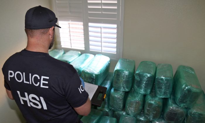 This photo provided by U.S. Immigration and Customs Enforcement shows an investigator Wednesday, March 23, 2016, viewing bags of marijuana stored in a room of a newly-built home in Calexico, Calif., the terminus of a cross-border tunnel that runs the length of four football fields to a restaurant in Mexicali, Mexico. (U.S. Immigration and Customs Enforcement via AP) 