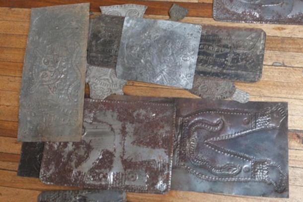 Carved metallic plates from Father Crespi's collection strewn on the floor in a dilapidated old building. (Ancient-Origins.net)
