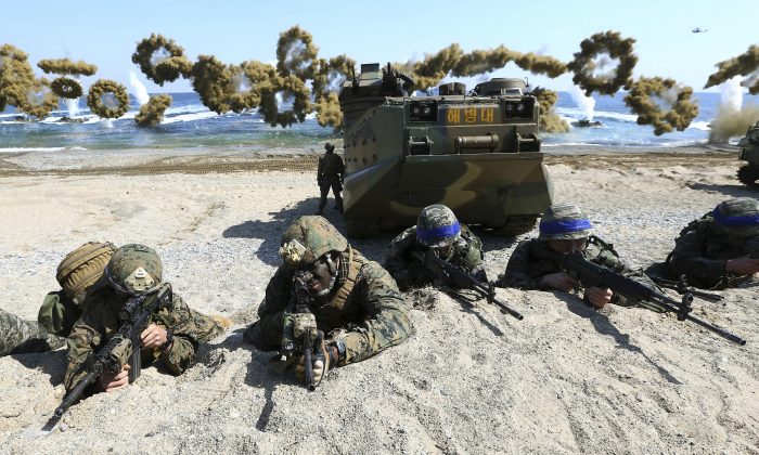 U.S. Marines (L) and South Korean Marines, wearing blue headbands on their helmets, take positions after landing on the beach during the joint military combined amphibious exercise, called Ssangyong, part of the Key Resolve and Foal Eagle military exercises, in Pohang, South Korea, on March 12, 2016. (Kim Jun-bum/Yonhap via AP)