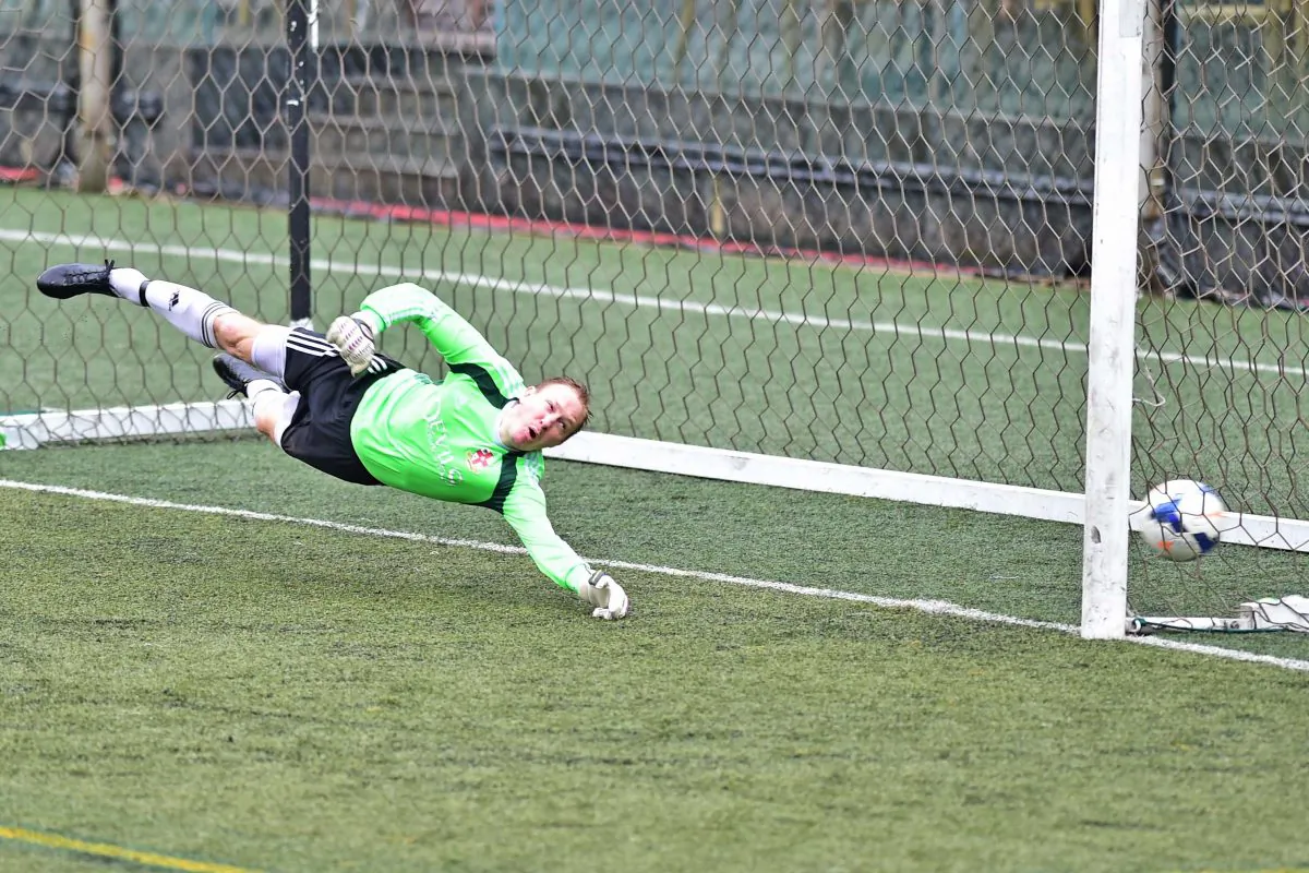 GAS goalkeeper Adam Bilbey narrowly misses this penalty strike awarded to Wanderers for a GAS hand-ball offence in the penalty area after 22 minutes of play, setting Wanderers on track for a 3-nil win in the final round of season in the Yau Yee league first division at Sports Road on Sunday April 24, 2016. (Bill Cox/Epoch Times)