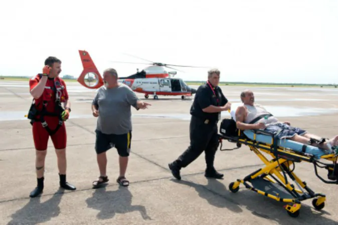 Petty Officer 2nd Class Jesse Weaver and survivor Michael Watkins speak as survivor Raymond Jacik is wheeled away by EMS after having been missing for more than two days in Galveston Bay, April 27, 2016. The two men were reported missing Tuesday morning after they didn't return home Monday afternoon becuase their boat had capsized in Trinity Bay. U.S. Coast Guard (photo by Petty Officer 3rd Class Dustin R. Williams)
