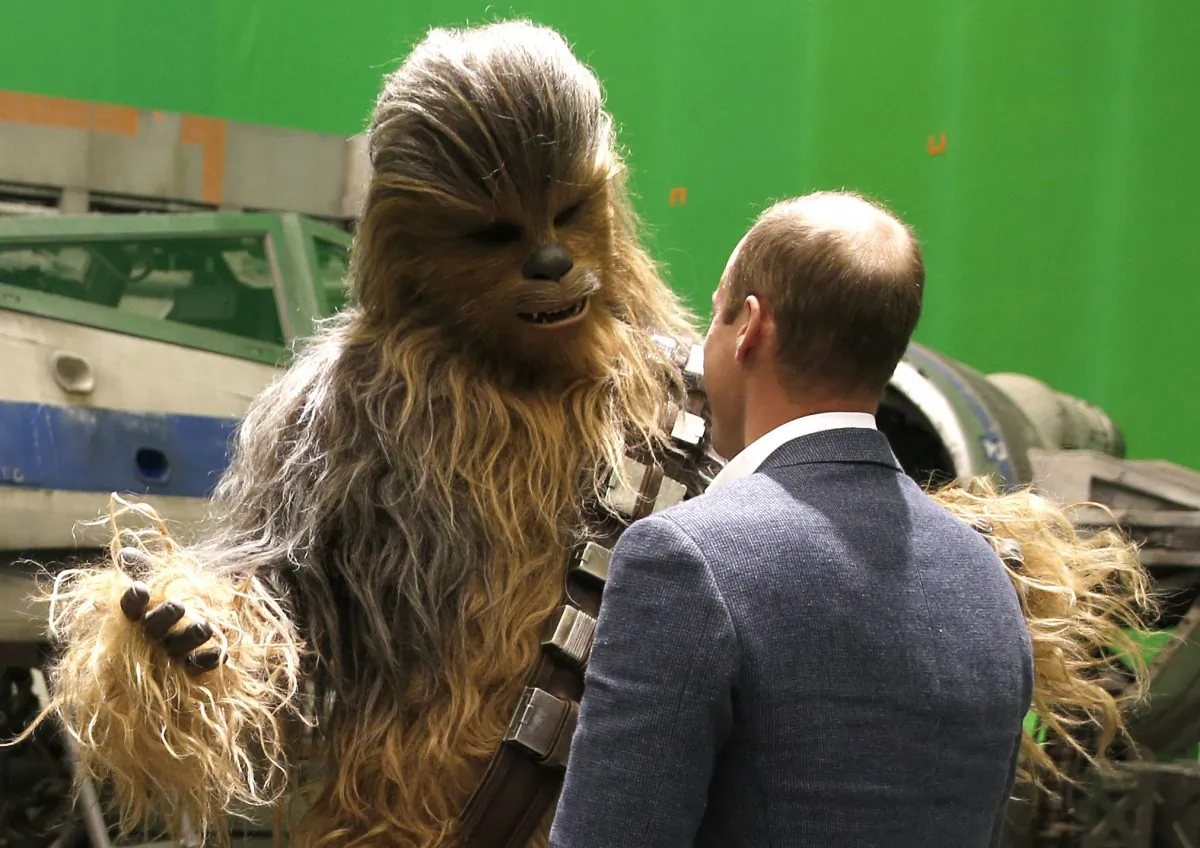 Britain's Prince William, talks with the Star Wars character Chewbacca during a tour of the Star Wars sets at Pinewood studios in Iver Heath, west of London on Tuesday April 19, 2016. Prince William and Prince Harry toured Pinewood to visit the production workshops and meet the creative teams working behind the scenes on the Star Wars films. (Adrian Dennis, Pool via AP)