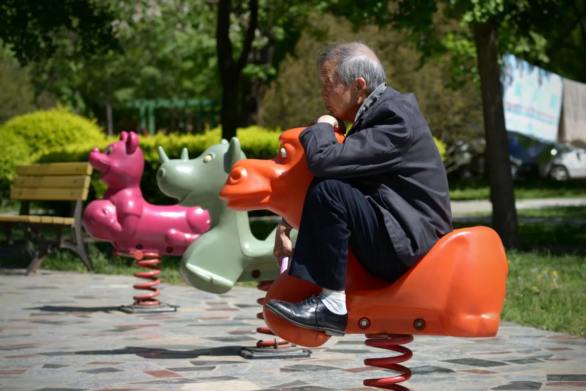 An elderly man sits on a hobby horse at a residential area in Beijing on May 4, 2015.  (WANG ZHAO/AFP/Getty Images)