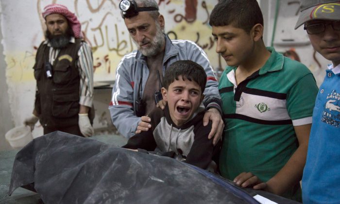A Syrian boy is comforted as he cries next to the body of a relative who died in a reported airstrike on April 27 in the rebel-held neighbourhood of al-Soukour in the northern city of Aleppo. (Karam Al-Masri/AFP/Getty Images)       