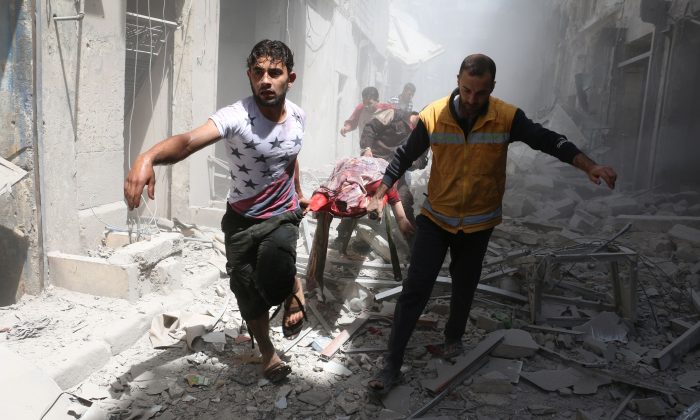 Syrian men carry a body on a stretcher amid the rubble of destroyed buildings following a reported air strike on the rebel-held neighbourhood of Al-Qatarji in the northern Syrian city of Aleppo, on April 29, 2016.
(Ameer Alhalbi/AFP/Getty Images)