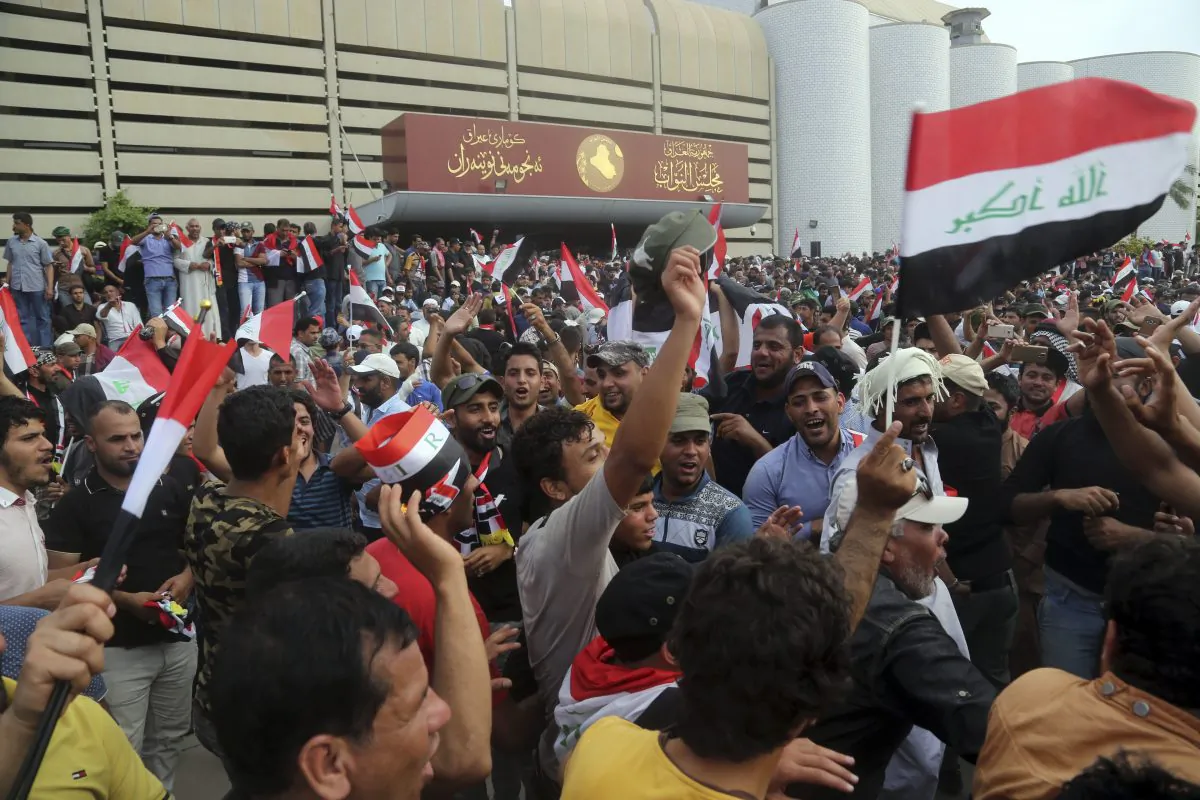 Supporters of Shiite cleric Muqtada al-Sadr raise the Iraqi flags outside parliament in Baghdad's Green Zone on April 30, 2016. Dozens of protesters climbed over the blast walls and could be seen storming the Parliament building, carrying Iraqi flags and chanting against the government. (AP Photo/Khalid Mohammed)