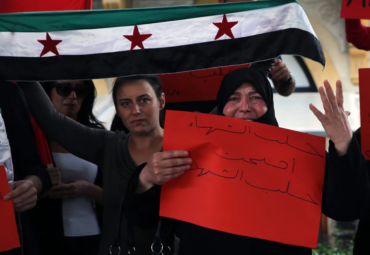 A Syrian woman weeps as she holds an Arabic placard that reads "Aleppo has become the Aleppo of martyrs," during a protest in downtown Beirut, Lebanon, on April 30, 2016, against Syrian President Bashar Assad's military operations against areas held by insurgents around the country, mostly in the northern city of Aleppo that has been the main point of violence. (AP Photo/Bilal Hussein)