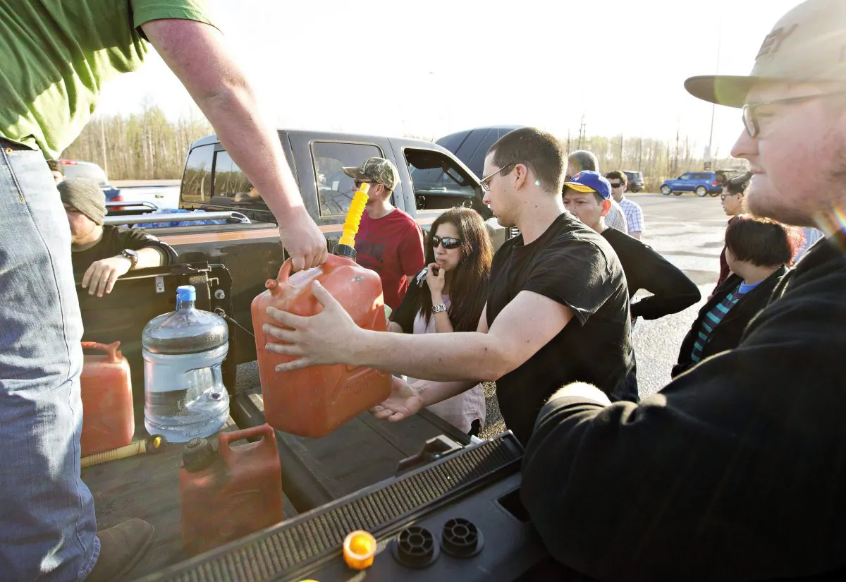 People gather to get gas and water being handed out at a rest stop near Fort McMurray for those fleeing the wildfire on May 4, 2016. (The Canadian Press/Jason Franson)
